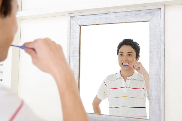 力を入れて歯磨きをしている男性の画像